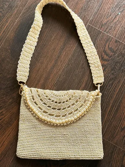 This elegant gold bag, detailed with delicate pearls, is designed to be your go-to accessory. It effortlessly complements both ethnic and western outfits, adding a touch of glamour to any look.