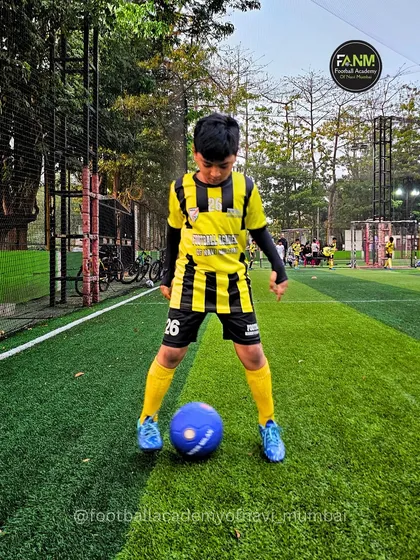 A young player stands over the ball, focused and ready for the next instruction.
