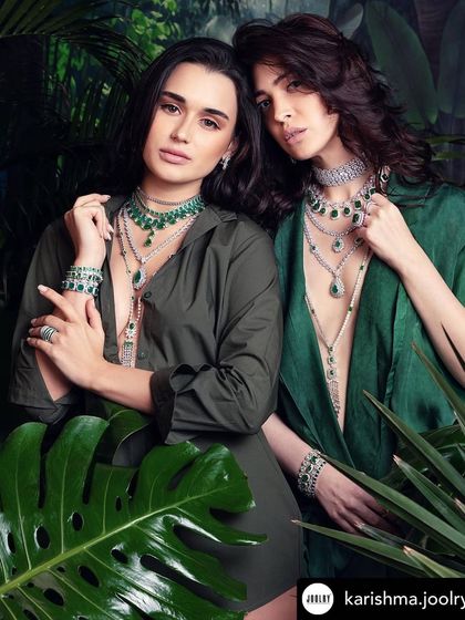 A lush, green-themed shot for Karishma Joolry's 'Forest' collection, with two models layered in stunning emerald and diamond pieces.