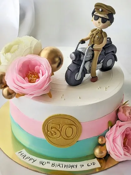 This cake was made for an actress celebrating her role as a police inspector. It features a custom, hand-sculpted figurine of her character on a motorcycle, combined with soft floral elements for a beautiful contrast.