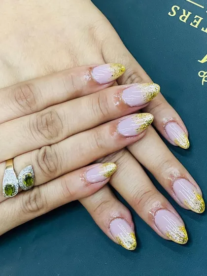 Get ready for any celebration with our festive nail designs. Here, we've applied a sparkling gold glitter fade over a sheer pink base on almond-shaped nails, offering a glamorous and eye-catching look that’s perfect for parties and special events.