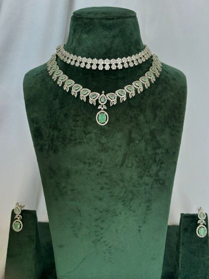A delicate American diamond necklace set with green stone accents. This rental piece adds a subtle touch of colour to the sparkling design.