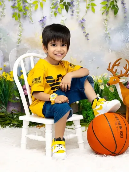 Posing with confidence in our garden set. This young boy's bright and cheerful personality is a perfect match for this colorful basketball-themed photoshoot.