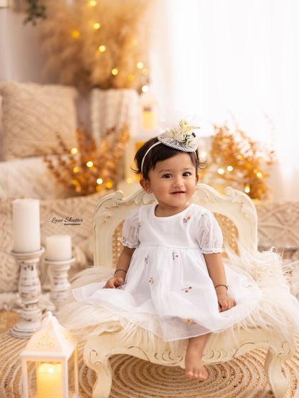 A classic portrait of the birthday girl sitting on a vintage chair in our warm, candlelit boho set.