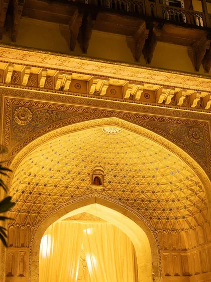 The intricately carved and beautifully lit ceiling of an archway at Chomu Palace, showcasing the incredible heritage architecture that serves as a backdrop for our events.
