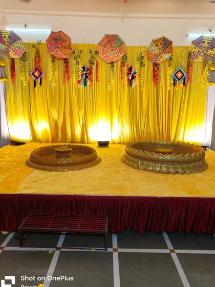 A Haldi stage with two baithaks for the bride and groom. The backdrop is decorated with yellow drapes and traditional umbrellas, perfect for a joint ceremony.