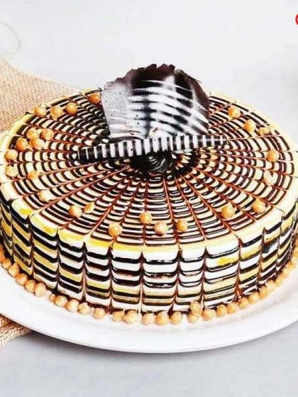 This butterscotch cake features an intricate spiderweb design made with chocolate and caramel. Topped with crunchy butterscotch beads, it offers a delightful combination of textures and sweet flavours.