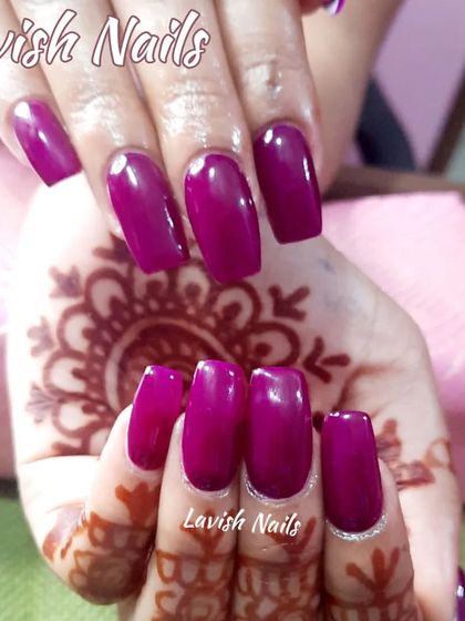 A classic bridal choice of deep magenta nails on a hand with henna, offering a rich and traditional look.