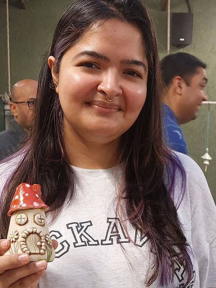 A customer at the Studio Potters' Market holding one of my mushroom fairy house tealight holders. These pieces add a touch of fairytale magic to any room.
