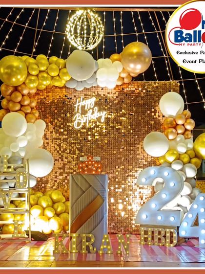 A glamorous 24th birthday celebration with an outdoor setup. The decor features a gold sequin wall, a 'Happy Birthday' neon sign, and a gold and white balloon arch.