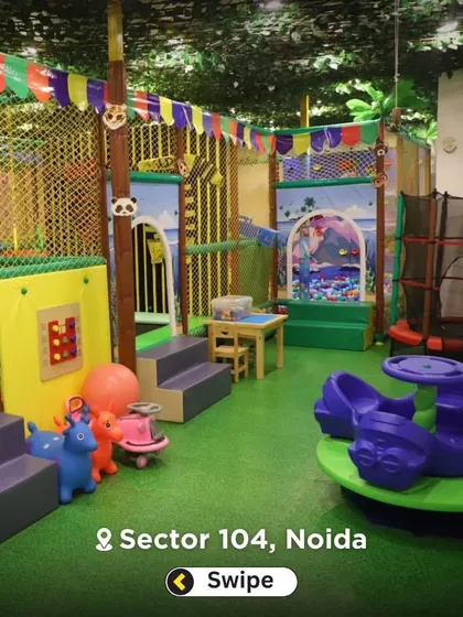 A wide shot of the toddler play area, complete with soft flooring, rockers, and a small play structure. It's a self-contained space for safe fun.