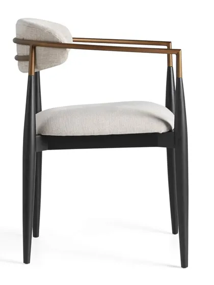 A side profile of the Jagger armchair, highlighting the contrast between the dark mahogany frame, the warm metal, and the light upholstery.