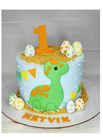 A cute baby dinosaur cake for a first birthday. This chocolate truffle Ferrero Rocher cake has handmade fondant dinosaur eggs and a friendly dino character.