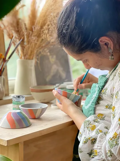 A student paints delicate, colorful stripes on a set of bowls, a highlight from a week of easing back into the studio rhythm.