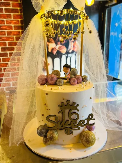 A "Sweet 16" birthday cake with a lighted canopy and a delicate tulle veil.