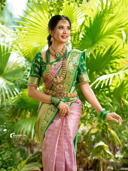 A candid shot of a model in a traditional silk saree, capturing a natural and happy expression against a lush green backdrop.