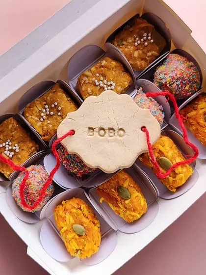 This is a close-up of my 'OG' Rakhi mithai box. It's filled with dog-friendly versions of Indian sweets like pumpkin pedas and carrot burfi, and of course, the edible rakhi biscuit personalized with your dog's name.