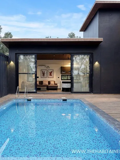 The pool deck of a container home, with the living room opening directly onto the outdoor space for a seamless indoor-outdoor lifestyle.