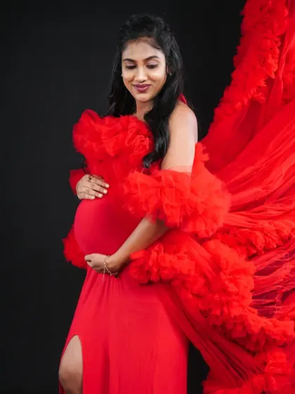 A closer look at the ruffled shoulder details and flowing fabric of our statement red gown, perfect for capturing powerful pregnancy portraits.