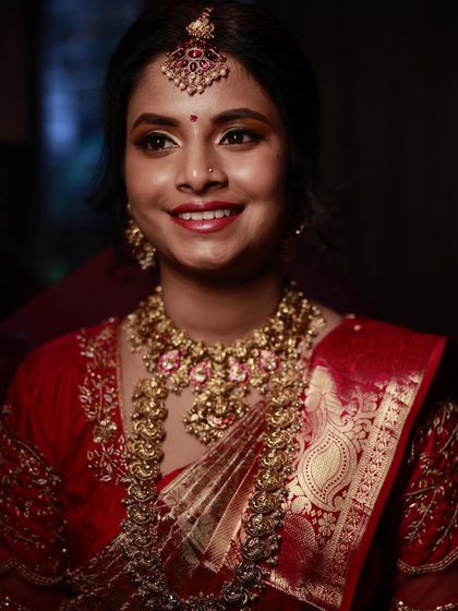 A smiling portrait of the bride, showcasing her complete traditional look with heavy jewellery and radiant makeup.