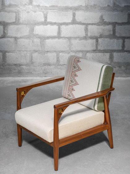 The Makam Lounge Chair, featuring a combination of wood, brass detailing, and hand-block printed fabric. It's a fine example of subtle detailing, making it an ideal conversation starter for your living space.
