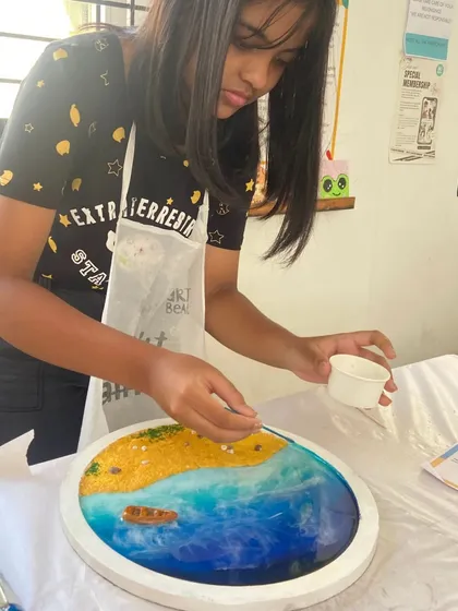 A participant works on her resin beach art, adding shells and texture to the sand. Every piece is a unique creation.
