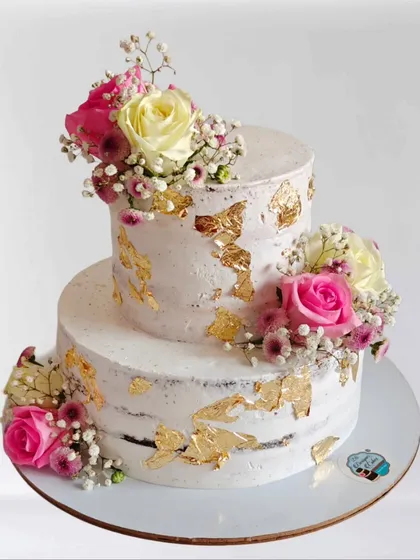 A rustic semi-naked cake decorated with fresh flowers and gold leaf. This style is very popular for weddings and anniversaries due to its natural and effortless beauty.