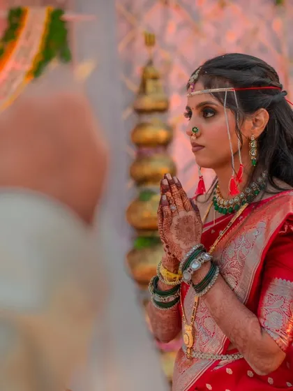 A candid photograph capturing the solemnity of the wedding ceremony. The bride's side profile highlights the hairstyle and the placement of the traditional 'mundavalya'.