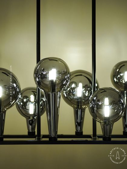 A playful yet chic linear chandelier featuring a series of chrome-finished glass bubbles. The highly reflective surface and modern design make it a striking addition to a kitchen island or a contemporary dining space.