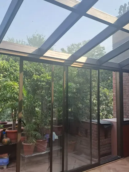This glass-enclosed sunroom is a perfect example of how we create seamless indoor-outdoor transitions. The floor-to-ceiling glass walls and transparent roof flood the space with natural light, making it a perfect year-round garden room.