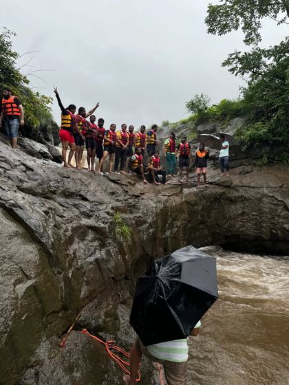 A group wearing life jackets, ready for a thrilling water activity at the base of a waterfall in Maharashtra.