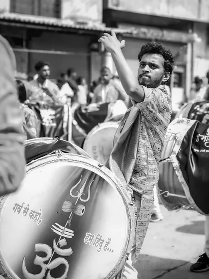 A black and white shot of a dhol player with an intense, focused expression.