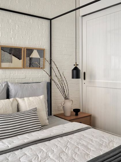 As the daughter’s favorite color was white, I designed her bedroom with a white theme and a four-poster bed. The metal bed stands out against a rustic white brick wall, with oak wood side tables for warmth.