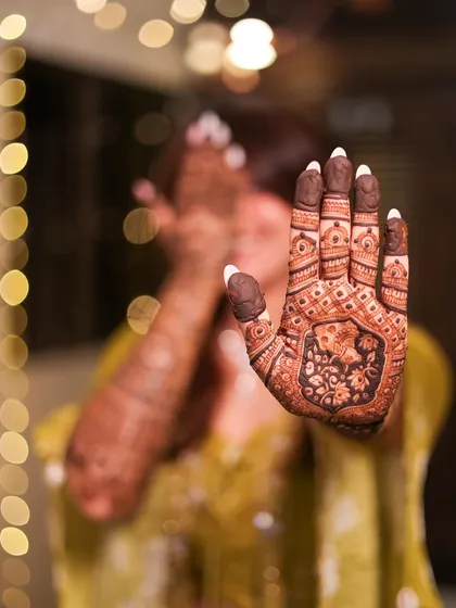 A close-up shot focusing on the intricate details of the bridal mehendi. The rich stain is just beginning to develop, promising a beautiful dark color for the wedding day.