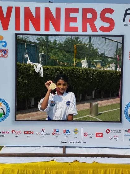 A gold medalist poses in the winner's frame, celebrating her victory.