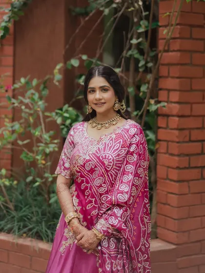 A full shot of the bride in her beautiful pink bandhani outfit. The makeup is soft and glowing, a timeless look that every girl dreams of.