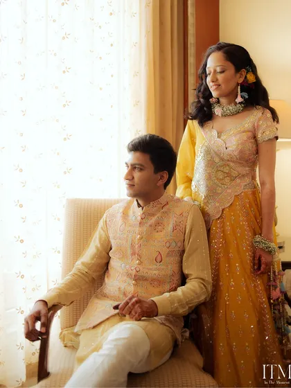 A soft and elegant indoor portrait. The natural light from the window and the couple's relaxed pose create a timeless and romantic image from their celebration at The Lalit, Mumbai.