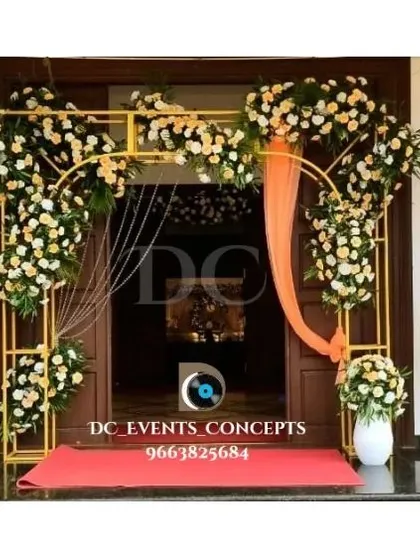 An elegant entrance decor setup for a home-based event. The golden frames adorned with white and peach florals create a sophisticated and welcoming doorway.