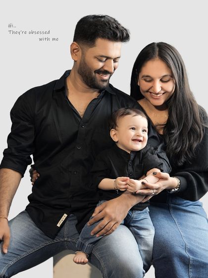 A happy family portrait where the parents' loving gaze is all on their smiling baby. The caption "Hi... They're obsessed with me" adds a touch of humor.