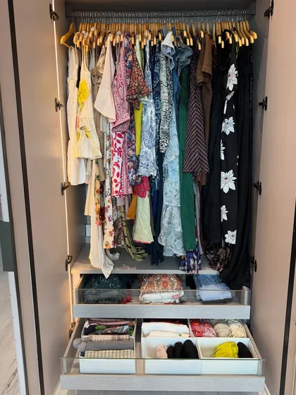 A wardrobe section dedicated to women's apparel, with dresses and tops hanging above drawers containing neatly organized smaller items.