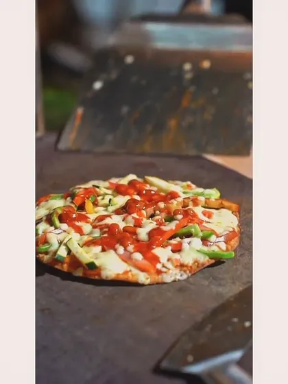 A freshly made Mexican Chipotle Pizza, ready to be sliced and served. The rustic presentation on a wooden board adds to its appeal.