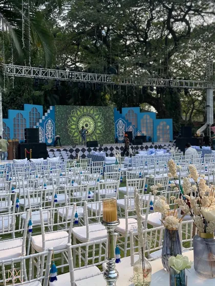 A wide shot of the blue and white themed stage and guest seating, creating a royal and expansive feel in the outdoor venue.