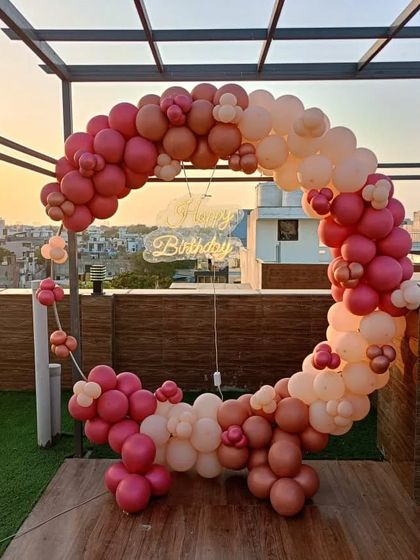 A beautiful balloon ring decoration on a rooftop terrace. The arch, in shades of dusty rose and blush, is set against a city skyline, making it perfect for a sunset birthday party.