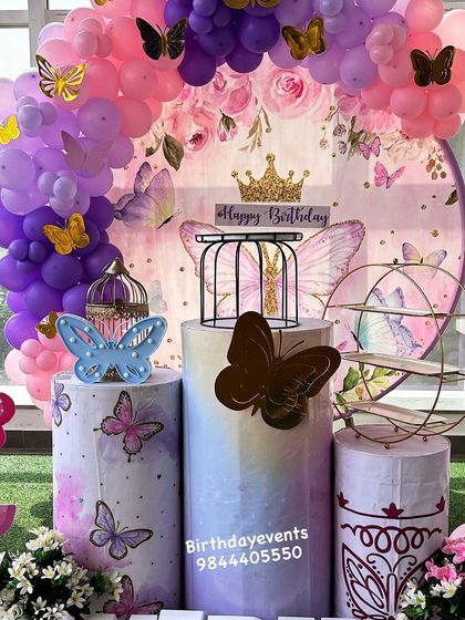 A detailed shot of the dessert table setup for a butterfly-themed party. It features themed plinths, decorative bird cages, and a tiered stand, all ready for the birthday treats.