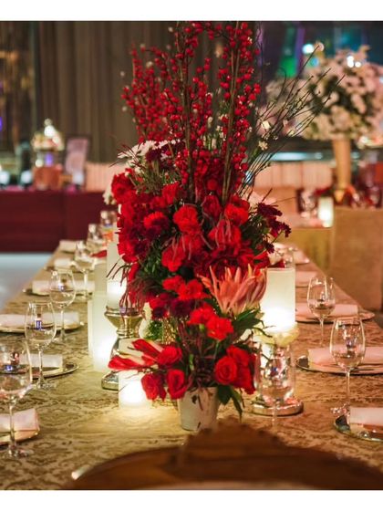 Another perspective of the opulent red-themed dining table, highlighting the rich brocade tablecloth and ambient candle lighting that create a warm and inviting atmosphere.