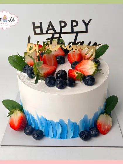 A simple and elegant cake topped with fresh strawberries and blueberries, with a beautiful blue brushstroke effect on the side.