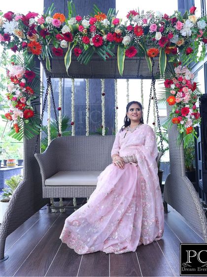Another beautiful shot of the mom-to-be on the floral swing. The natural light and lush greenery in the background complement the fresh flower decor perfectly.
