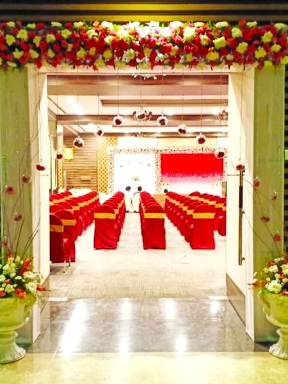 A flower decoration for a party hall entrance. The doorway is framed with a floral border, and the path is marked by a red carpet.