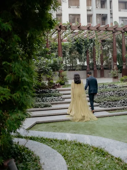 A beautiful shot of the couple walking away, highlighting the dramatic cape of the bride's gown.