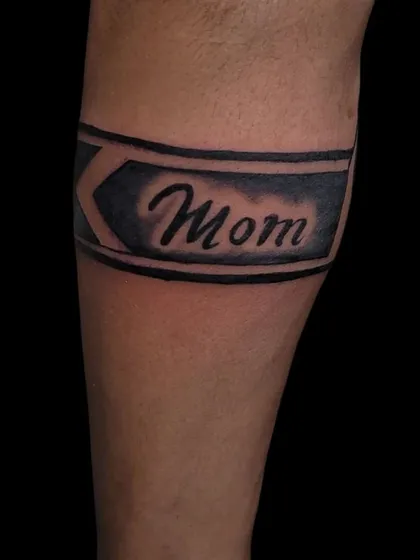 A "Mom" tattoo designed as part of a simple armband.